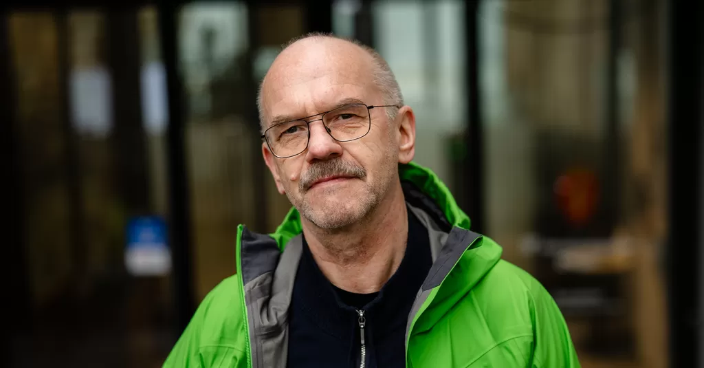 Portrett av en mann med briller og grønn jakke.